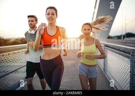 Montare atletico amici esercizio e jogging insieme all'esterno. Sport, gli amici, il concetto di salute Foto Stock