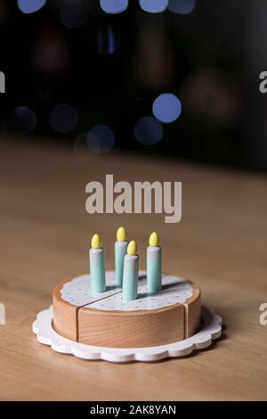 Toy festa di compleanno torta isolato su una superficie in legno su uno sfondo scuro con faretti Foto Stock