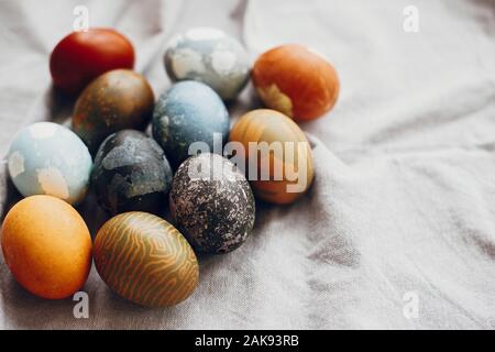 Elegante uova di pasqua sul tavolo rustico. Tinte naturali colorate uova di pasqua sulla biancheria rurale sfondo tessili. Spazio per il testo Foto Stock