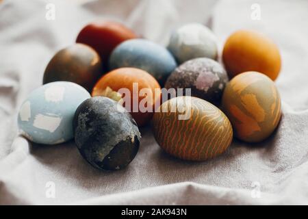 Elegante uova di pasqua sul tavolo rustico. Tinte naturali colorate uova di pasqua sulla biancheria rurale sfondo tessili. Spazio per il testo Foto Stock