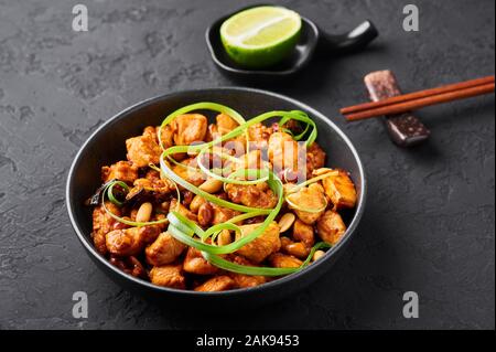 Kung Pao o pollo Gong Bao Ji Ding in ardesia scuro dello sfondo. Sichuan Kung Pao è la cucina cinese è piatto con carne di pollo, peperoncino, arachidi, sa Foto Stock