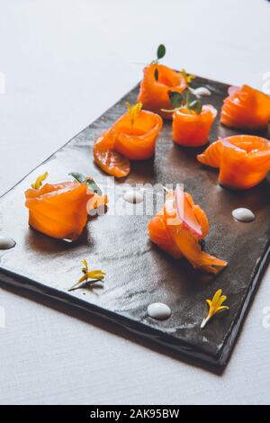Fette di Salmone su nero di lastre di ardesia, sushi pesce crudo Foto Stock