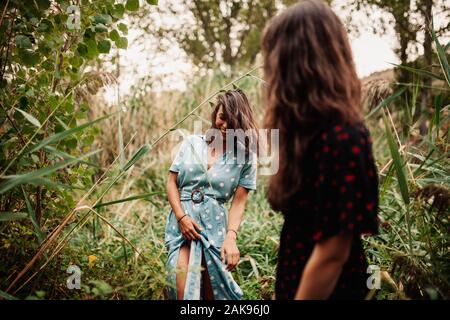 Due giovani donne a piedi attraverso il campo Il campo di indossare abiti e scarpe da ginnastica Foto Stock