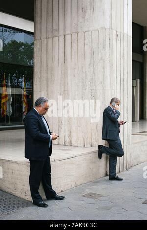 Due brokers utilizzando i loro telefoni cellulari nella parte anteriore del mercato azionario in Barcellona, Spagna Foto Stock