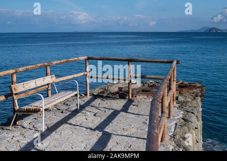 Svuotare panca in legno e ringhiera di fronte al mar Mediterraneo a Sant'Andrea, Isola d'Elba e Arcipelago Toscano, Italia Foto Stock