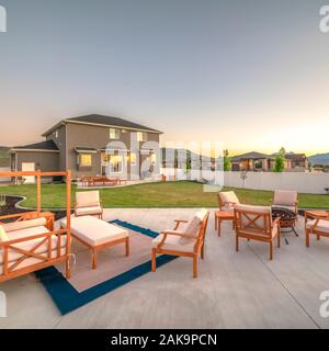 Cornice quadrata mobili in legno presso il patio del grigio di una casa contro la montagna e il cielo al tramonto Foto Stock
