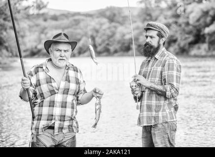 Torna alle nostre radici. Il campeggio sulla riva del lago. Big game fishing. amicizia. Il turismo di caccia. padre e figlio di pesca. Due felice pescatore con canna da pesca e net. Pesca a Mosca Tempo. hobby. Foto Stock