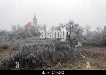 Frosty alberi e cespugli intorno alla chiesa di Sajopuspoki su una giornata invernale in Ungheria. Foto Stock