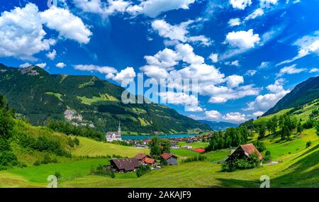 Panorama del villaggio svizzero di Lungern con chiesa e tradizionali case di legno sul lago Lungernsee nella soleggiata giornata estiva, Obvaldo, Svizzera Foto Stock