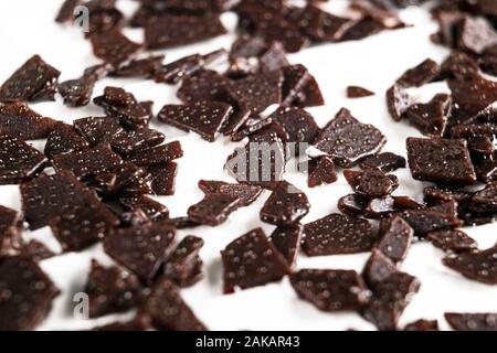 Il cioccolato grattugiato. Pila di massa di cioccolato isolato su sfondo bianco. Schiacciato il cioccolato fondente isolato su bianco. Scaglie di cioccolato amaro di chocol Foto Stock