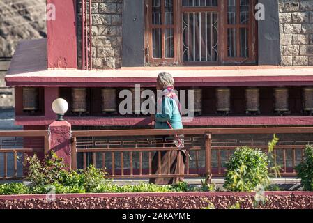 Vecchia donna la filatura ruote della preghiera in Kag contese Thupten Samphel Ling monastero nel villaggio di Kagbeni, Mustang distretto, Nepal. Foto Stock