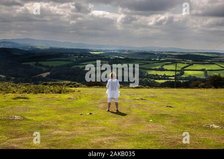 Donna che guarda sulla vallata verso cardinham legno, Bodmin Moor, Cornovaglia Foto Stock