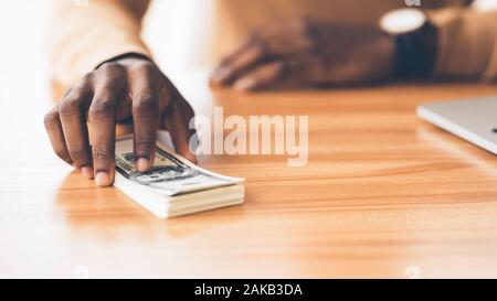 La venalità concetto. Irriconoscibile imprenditore africano holding mazzetto di centinaia di fatture del dollaro, spazio copia, panorama Foto Stock