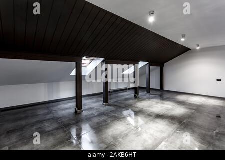 Vuoto non ammobiliato loft mansarda sala interna con colonne di legno e calcestruzzo bagnato pavimento sul livello del tetto in nero e stile whote colore Foto Stock