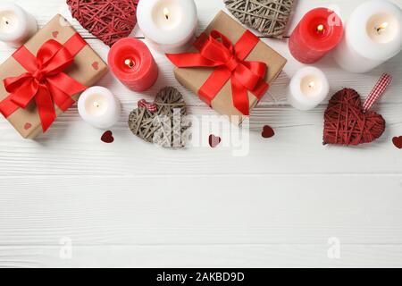 Confezioni regalo, candele e cuori in bianco sullo sfondo di legno, lo spazio per il testo Foto Stock