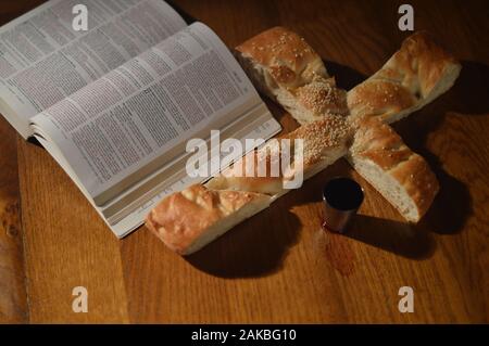 Pane a forma di croce con una Bibbia aperta a Luca 22 e un calice di vino Foto Stock