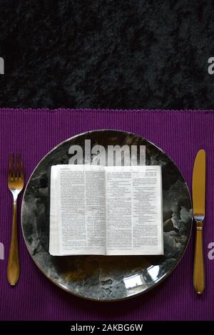 La Bibbia aperta fino a Matteo 4:4 su una piastra di cena su un cartellone viola con argenti in quaresima Foto Stock