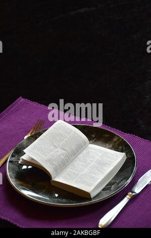 La Bibbia aperta fino a Matteo 4:4 su una piastra di cena su un cartellone viola con argenti in quaresima Foto Stock