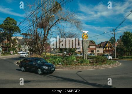 Auto sulla rotatoria e giardino con il Rotary International logo sul piedistallo a Gramado. Un simpatico unione-influenzato città nel sud del Brasile. Foto Stock