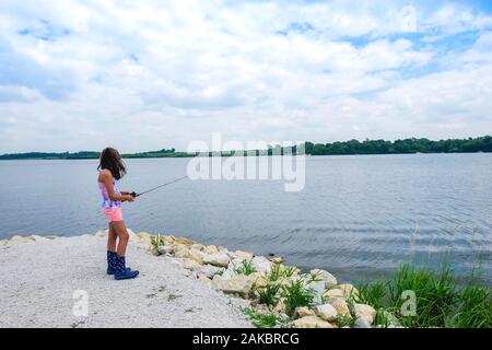 Adolescente ragazza 10-12 anni in piedi vicino alla pesca d'acqua il giorno d'estate Foto Stock