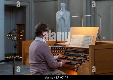 L'Islanda, la regione della capitale, Reykjavik, Hallgrimskirkja, uomo giocando l'organo, organo a canne progettato dal tedesco organaro Johannes Klais Foto Stock