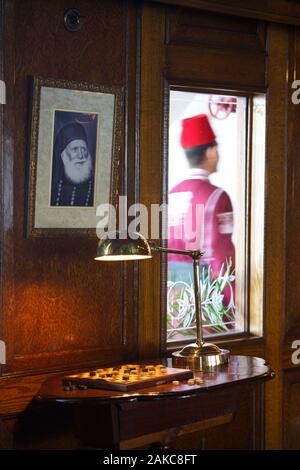 Egitto Alto Egitto, Valle del Nilo, Nave a vapore Sudan lounge, l'ultimo battello a vapore sul Nilo, decorata con una foto in bianco e nero di un ex pacha egiziano, con un membro dell' equipaggio indossando un 'tarbouche passando in un corridoio Foto Stock