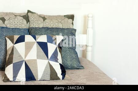Camera da letto arredo, blu e grigio i cuscini sono giacenti sul coperchio sul male in legno vicino alla parete bianca, casa accogliente in stile minimalista moderno interni scandinavo Foto Stock