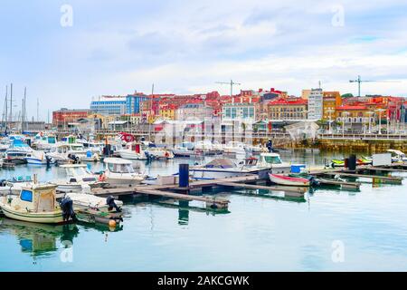 Nuvoloso citycsape con yacht e barche a motore ormeggiate dai piloni in marina, Gijon, Asturias, Spagna Foto Stock