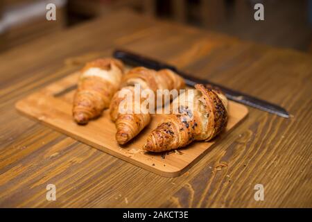Tre gustosi croissant burroso sul vecchio tavolo in legno Foto Stock