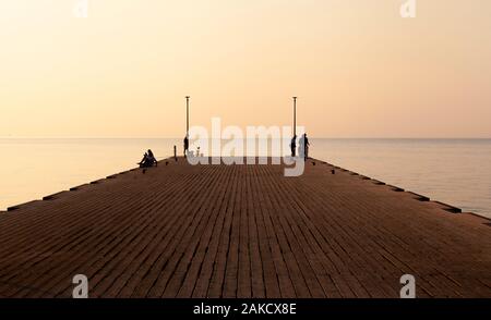 Il Molo sul Mare nelle prime ore del mattino con persone silhouette (vista in prospettiva) Foto Stock