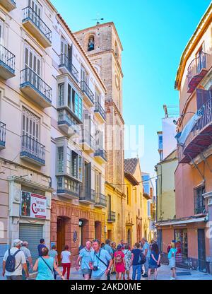 MALAGA, Spagna - 26 settembre 2019: affollato Calle Granada (street) con vecchi edifici alti e la torre campanaria a pianta quadrata di Santiago Apostol chiesa, sul set Foto Stock