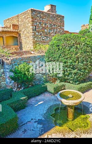 La piccola fontana di pietra in mezzo la topiaria da giardino del patio de la Surtidores (getti di acqua) in Alcazaba fortezza, Malaga, Spagna Foto Stock