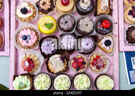 Una parte superiore verso il basso ritratto di un sacco di colorate e Deliziose tortine in diversi sapori e forme. Alcuni dolci di frutta hanno su di essi. Foto Stock