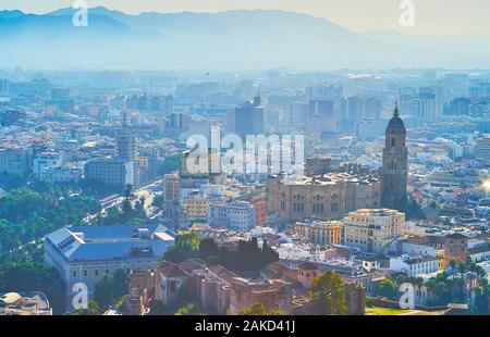 I bastioni del castello di Gibralfaro aprire la vista su Malaga città vecchia, coperto con haze; l'alto campanile della cattedrale che domina la città, Spagna Foto Stock