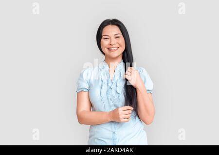 Freestyle. Donna asiatica in piedi isolato su bianco sorridente allegro Foto Stock