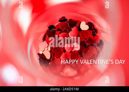 Cuori rossi sono sparsi in un bicchiere. Il giorno di San Valentino concetto Foto Stock