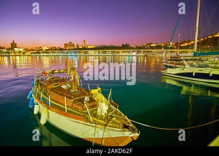 La linea di imbarcazioni ormeggiate nel porto di sera con illuminato e Cattedrale Alcazaba fortezza sul background, Malaga, Costa del Sol, Spagna Foto Stock