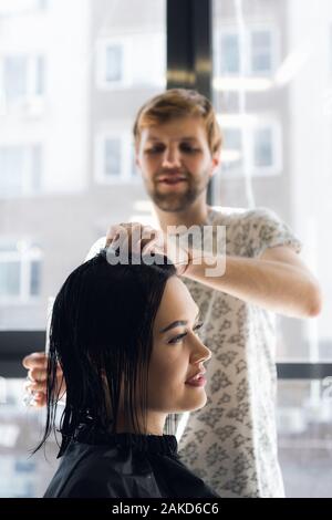 Parrucchiere lavora nel salone di parrucchiere il taglio donna capelli. Foto Stock