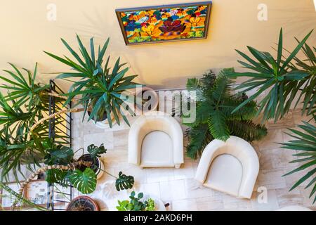 Interno del Hotel Pannonia, lounge con due beige poltrone in pelle e di piante in vaso top view, Sopron, Ungheria Foto Stock