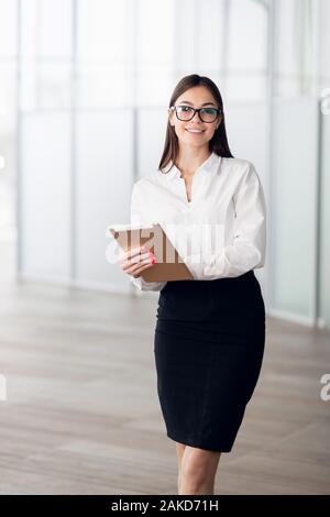 Uno stile di vita attivo di etnia miste carriera business donna a piedi per un posto di lavoro in ufficio. Foto Stock