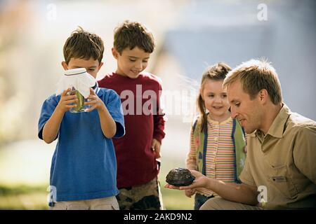 Ranger che mostra i ragazzi bug in un vaso e una tartaruga Foto Stock