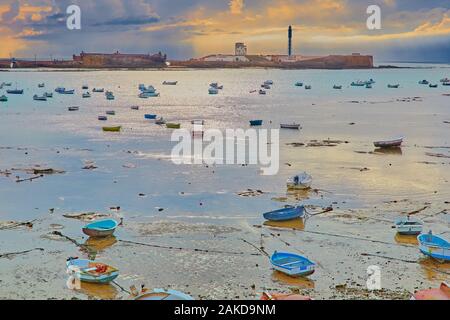 Abended barche nel paesaggio del tramonto sul bordo dell'Oceano Atlantico a Cadiz, Spagna Foto Stock