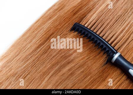 Spazzola per capelli neri dritti a Pettine capelli rosso su bianco Foto Stock