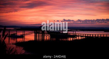 Cielo romantico su un molo e una barca al tramonto. Foto Stock