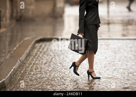 Businesswoman che porta la sua valigetta mentre cammina attraverso una strada pavimentata. Foto Stock