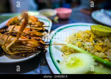 Bangkok/Thailand-December2019:gamberi alla griglia su una piastra con riso fritto su una piastra e salse in background in base a una tabella di notte a Chinatown Foto Stock