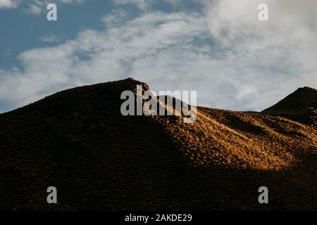 La luce dorata bagna una montagna di tussock vicino al Passo di Lindis, Nuova Zelanda Foto Stock