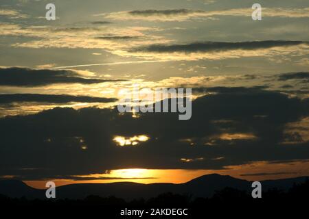 Sun impostazione luce dietro Massa di nuvole Foto Stock