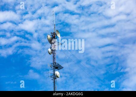 Un basso angolo di visione delle nubi sparse dietro una torre cellulare. Telecomunicazioni tecnologia elettronica e apparecchiature. Mobile phone booster di segnale. Foto Stock