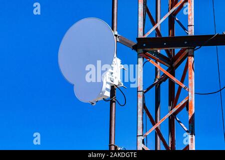 Primo piano e la vista dettagliata di un cerchio a microonde antenna fissa in acciaio al pilone a traliccio. Emissione di radiazione elettromagnetica legata a molti pericoli per la salute Foto Stock
